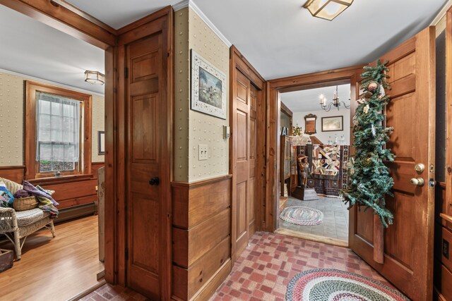 507 Ford Quint Rd, North Berwick, ME 03906 - entrance foyer featuring a chandelier, ornamental molding, a wainscoted wall, wooden walls, and wallpapered walls