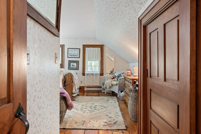 507 Ford Quint Rd, North Berwick, ME 03906 - bedroom featuring wallpapered walls, vaulted ceiling, wood finished floors, and a baseboard heating unit