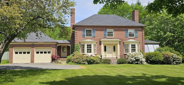 91 Mayflower Hill Dr, Waterville, ME 04901 - colonial home featuring a chimney, a garage, driveway, and a front yard