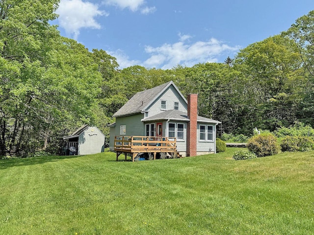 99 Huddle Rd, Bristol, ME 04554 - back of property with a chimney, a storage unit, a wooden deck, a yard, and a wooded view