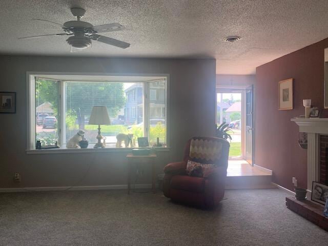 48 13th St, Bangor, ME 04401 - sitting room with a brick fireplace, carpet, a textured ceiling, and a ceiling fan