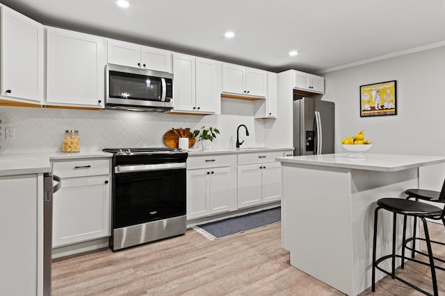 16 Guilford Ct Unit B1, Portland, ME 04101 - kitchen with appliances with stainless steel finishes, ornamental molding, light wood-style floors, a breakfast bar, and decorative backsplash