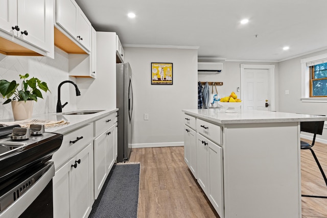 16 Guilford Ct Unit B1, Portland, ME 04101 - kitchen with a wall mounted air conditioner, freestanding refrigerator, stove, a center island, and light wood-style floors