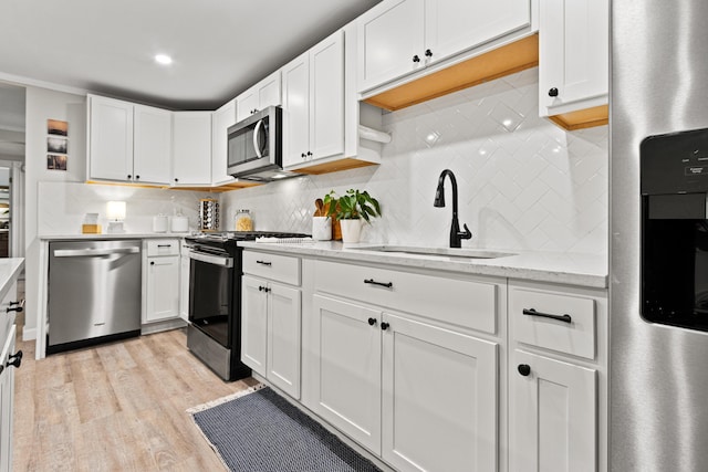 16 Guilford Ct Unit B1, Portland, ME 04101 - kitchen featuring stainless steel appliances, decorative backsplash, white cabinets, and light wood-type flooring