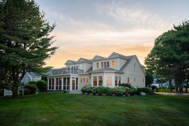 22 Channel Cove Ln, Biddeford, ME 04005 - back of property at dusk featuring a sunroom, a balcony, and a lawn