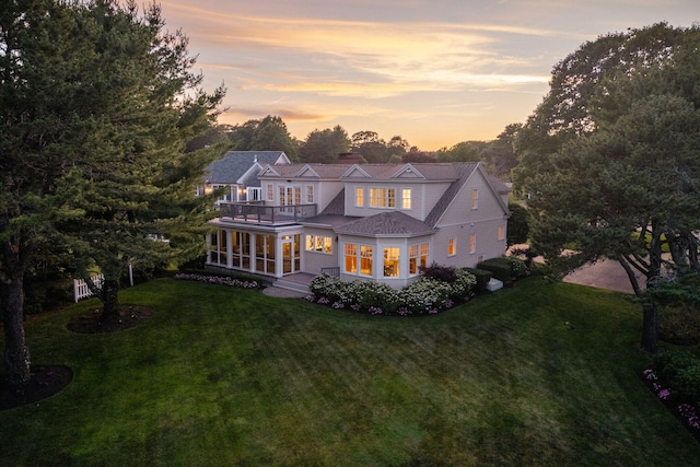 22 Channel Cove Ln, Biddeford, ME 04005 - back of house at dusk with a balcony, a lawn, and a chimney