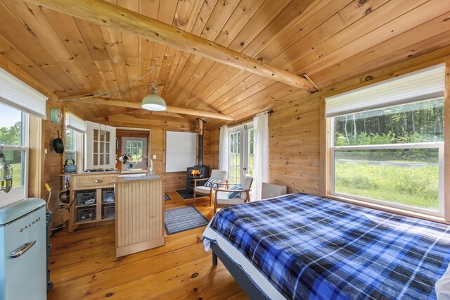 1535 Bailey Rd, Knox, ME 04986 - bedroom with a wood stove, wooden walls, light wood finished floors, and wood ceiling
