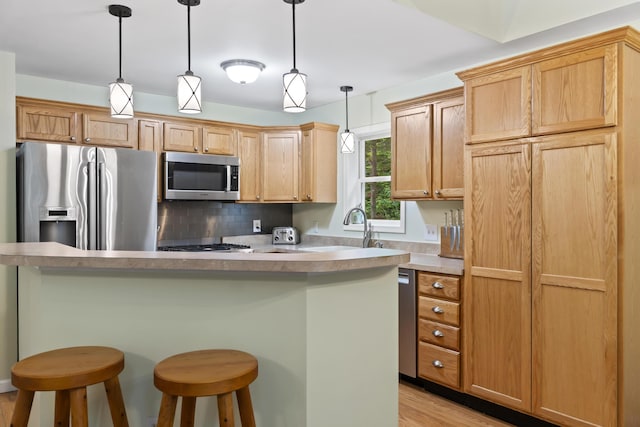 47 Double M Ln, Woolwich, ME 04579 - kitchen with stainless steel appliances, a breakfast bar, backsplash, light wood-style floors, and decorative light fixtures