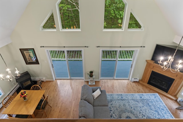 47 Double M Ln, Woolwich, ME 04579 - living room featuring a chandelier, high vaulted ceiling, a glass covered fireplace, wood finished floors, and plenty of natural light