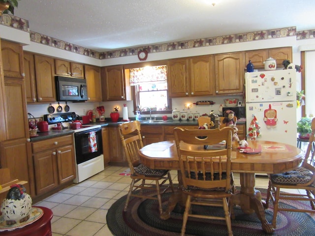 242 Newport Rd, Corinna, ME 04928 - kitchen featuring black microwave, electric range, freestanding refrigerator, brown cabinetry, and dark countertops