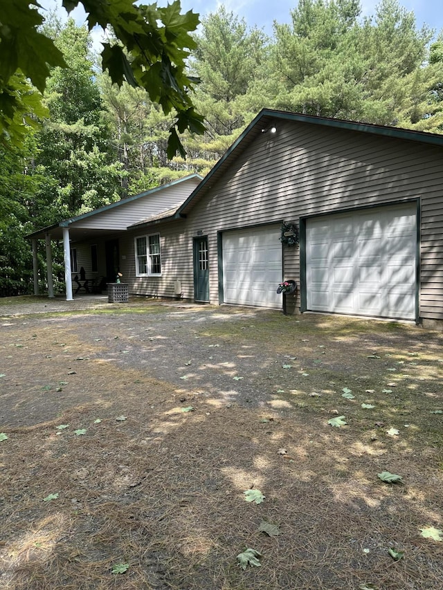 242 Newport Rd, Corinna, ME 04928 - ranch-style house with dirt driveway, an attached garage, and view of scattered trees