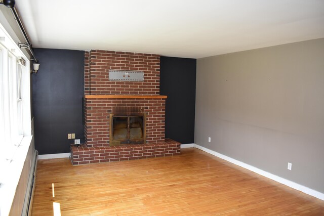 25 Ariel St, Lincoln, ME 04457 - unfurnished living room featuring wood finished floors and a brick fireplace