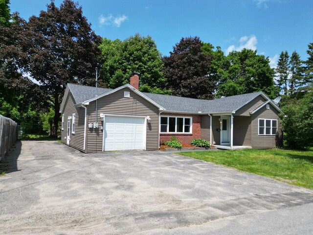 25 Ariel St, Lincoln, ME 04457 - ranch-style home featuring an attached garage, driveway, a chimney, roof with shingles, and brick siding
