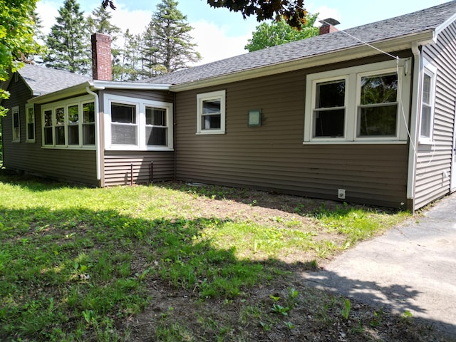 25 Ariel St, Lincoln, ME 04457 - view of home's exterior with a chimney, a lawn, and a shingled roof