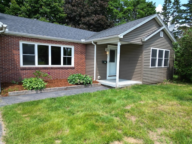 25 Ariel St, Lincoln, ME 04457 - ranch-style house featuring roof with shingles, brick siding, and a front yard