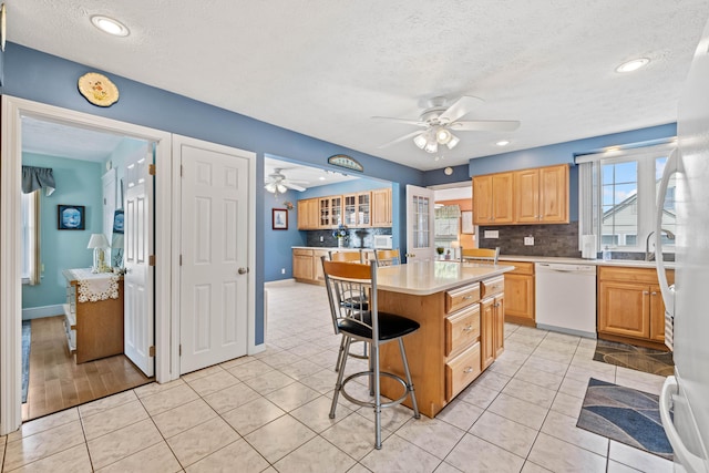 25 Harding St, Biddeford, ME 04005 - kitchen featuring white dishwasher, a ceiling fan, decorative backsplash, a breakfast bar, and a textured ceiling