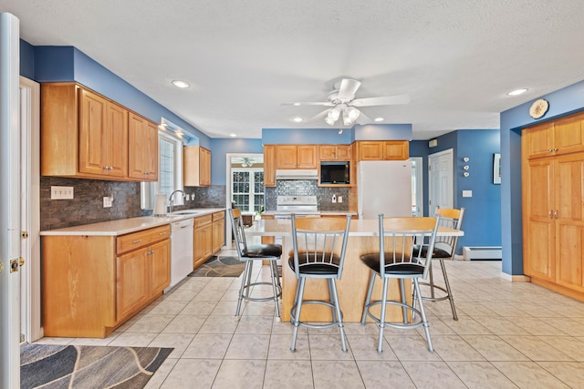 25 Harding St, Biddeford, ME 04005 - kitchen with white appliances, a baseboard heating unit, under cabinet range hood, backsplash, and a ceiling fan