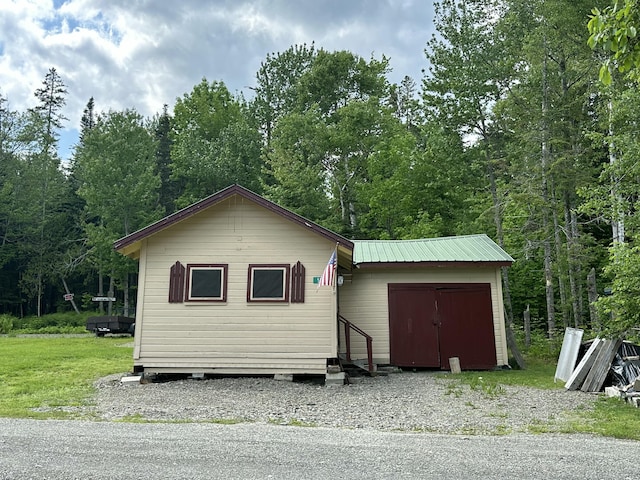 50 Forget Me Not Ln, Orient, ME 04471 - view of front of home featuring entry steps, a view of trees, a metal roof, and an outbuilding