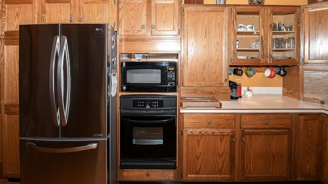 370 Center Conway Rd, Brownfield, ME 04010 - kitchen featuring black appliances, light countertops, glass insert cabinets, and brown cabinetry