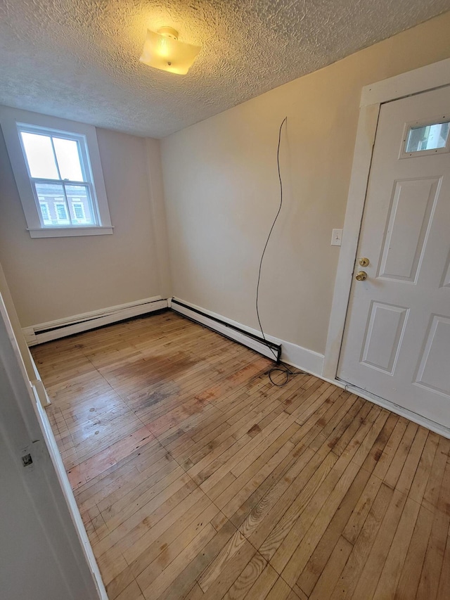 59 Washington St, Biddeford, ME 04005 - spare room featuring a baseboard radiator, wood-type flooring, a textured ceiling, and a baseboard heating unit