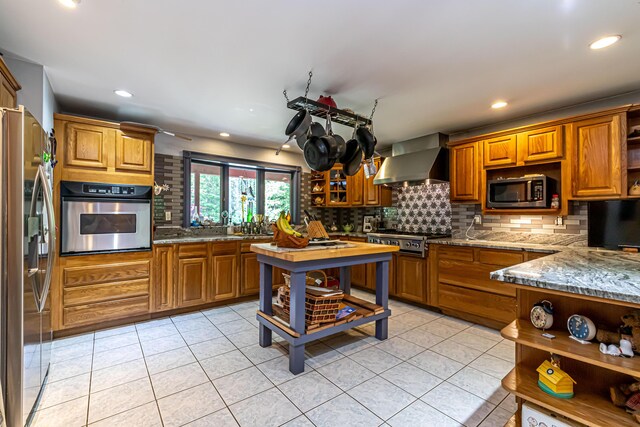 37 Paul St, York, ME 03909 - kitchen featuring stainless steel appliances, wall chimney range hood, open shelves, tasteful backsplash, and brown cabinetry