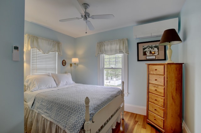 23 E Grand Ave, Scarborough, ME 04074 - bedroom with a wall unit AC, wood finished floors, and a ceiling fan