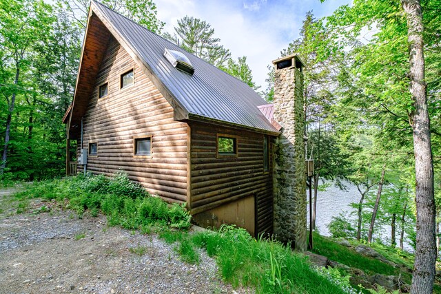 34 Alpine Shores Rd, Woodstock, ME 04219 - view of home's exterior featuring a chimney, a metal roof, faux log siding, and a water view