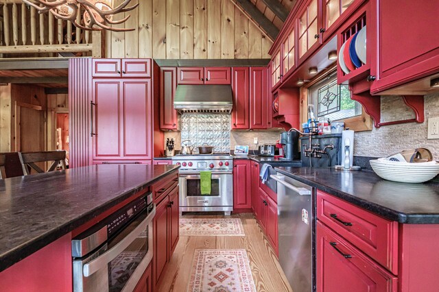 34 Alpine Shores Rd, Woodstock, ME 04219 - kitchen with stainless steel appliances, range hood, vaulted ceiling, dark countertops, and light wood-style floors