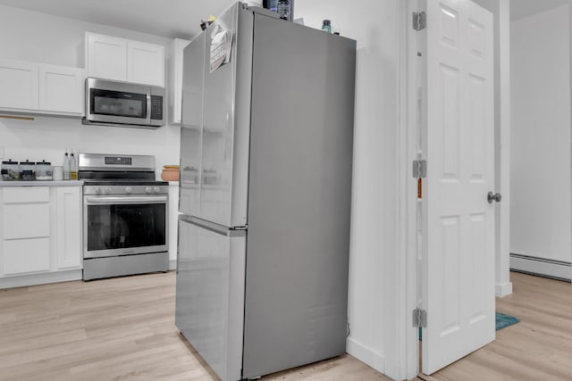 62 Seventh St, Auburn, ME 04210 - kitchen with stainless steel appliances, white cabinetry, light wood finished floors, and baseboard heating