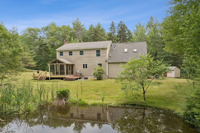 27 Libby Ln, Brunswick, ME 04011 - back of property featuring a sunroom, a deck with water view, a chimney, roof with shingles, and a lawn