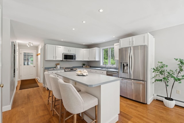 27 Libby Ln, Brunswick, ME 04011 - kitchen with appliances with stainless steel finishes, white cabinetry, a breakfast bar, light wood finished floors, and recessed lighting