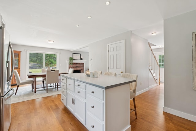 27 Libby Ln, Brunswick, ME 04011 - kitchen with a breakfast bar, stainless steel fridge with ice dispenser, a brick fireplace, white cabinets, and a center island