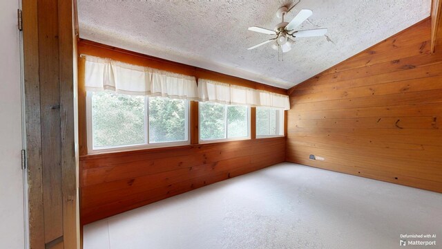 5 Wilson St, Lewiston, ME 04240 - carpeted empty room featuring plenty of natural light, a textured ceiling, lofted ceiling, and wooden walls