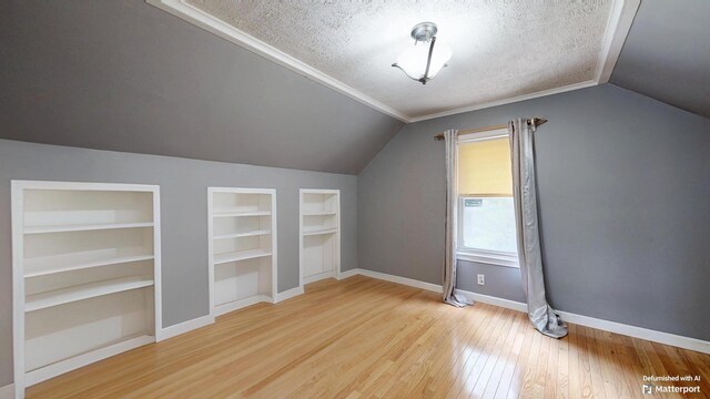 5 Wilson St, Lewiston, ME 04240 - additional living space featuring built in shelves, lofted ceiling, a textured ceiling, and hardwood / wood-style flooring