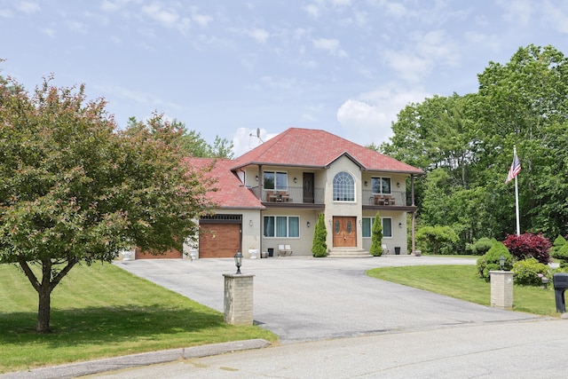6 Grande Ave, Lewiston, ME 04240 - mediterranean / spanish-style house with a balcony, asphalt driveway, a garage, a front lawn, and stucco siding