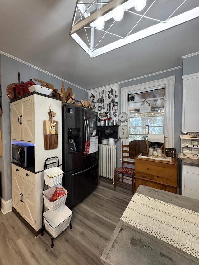 164 Lancey St, Pittsfield, ME 04967 - kitchen with black fridge with ice dispenser, radiator, ornamental molding, stainless steel microwave, and wood finished floors
