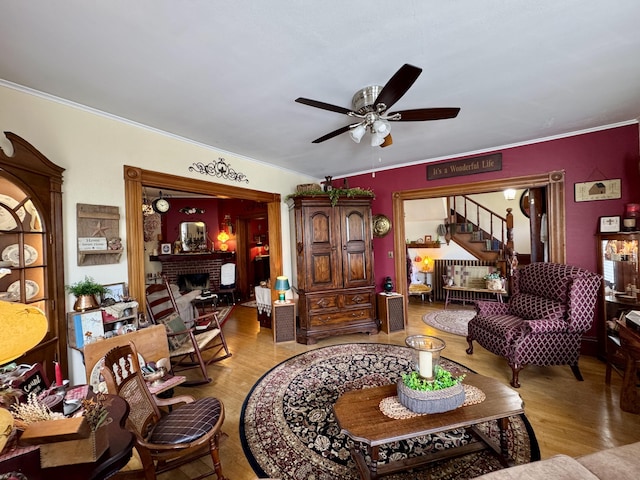 164 Lancey St, Pittsfield, ME 04967 - living room featuring a ceiling fan, stairway, a brick fireplace, wood finished floors, and ornamental molding