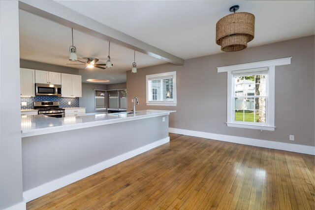 3 Dion St, Lewiston, ME 04240 - kitchen featuring appliances with stainless steel finishes, white cabinetry, hardwood / wood-style floors, backsplash, and decorative light fixtures