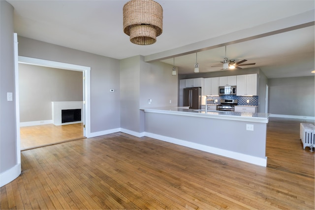 3 Dion St, Lewiston, ME 04240 - kitchen with appliances with stainless steel finishes, a peninsula, ceiling fan, tasteful backsplash, and white cabinetry