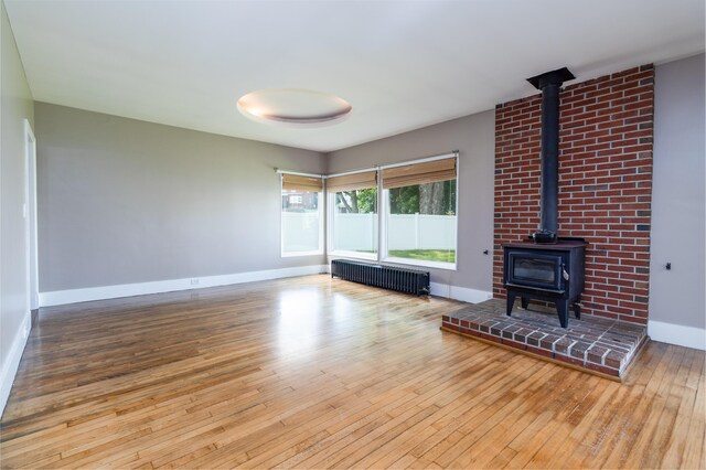 3 Dion St, Lewiston, ME 04240 - unfurnished living room featuring radiator, a wood stove, and hardwood / wood-style flooring