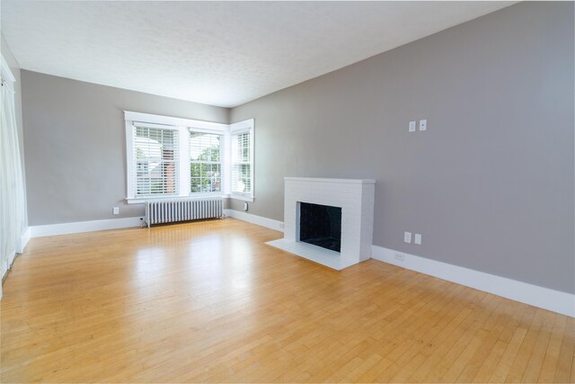 3 Dion St, Lewiston, ME 04240 - unfurnished living room featuring radiator, light wood finished floors, and a fireplace