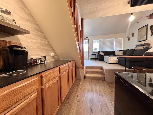 8 Fall Line Dr Unit N211, Newry, ME 04261 - kitchen with dark countertops, open floor plan, lofted ceiling, light wood-type flooring, and brown cabinets