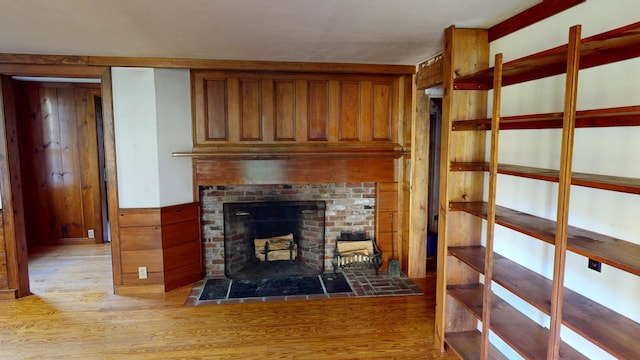 30 Wilkinson Ln, Machiasport, ME 04655 - unfurnished living room with light wood finished floors, a fireplace with flush hearth, wainscoting, and wood walls