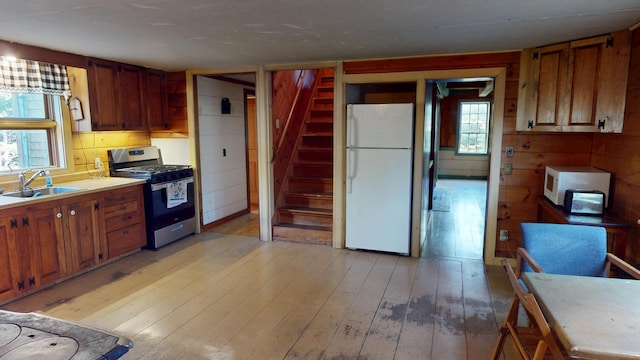30 Wilkinson Ln, Machiasport, ME 04655 - kitchen with white appliances, light wood-style flooring, light countertops, wood walls, and brown cabinetry