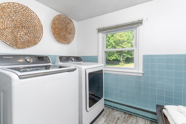 470 Main St, Waterville, ME 04901 - washroom featuring a baseboard heating unit, washer and clothes dryer, light wood-style floors, a wainscoted wall, and tile walls