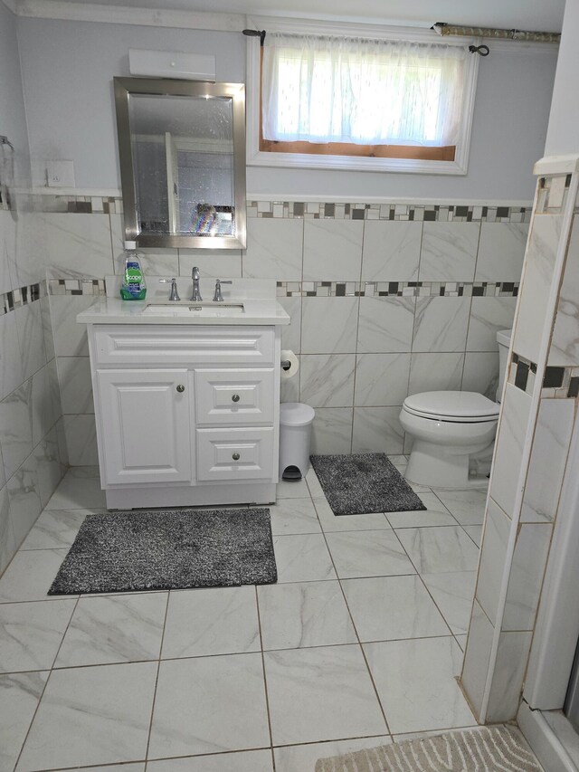 7 Lorraine Ave, Lewiston, ME 04240 - bathroom featuring tile walls, vanity, marble look tiles, and a wainscoted wall
