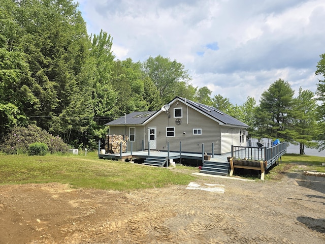 502 Cedar Lake Rd, Millinocket, ME 04462 - rear view of house featuring a deck, solar panels, and a lawn
