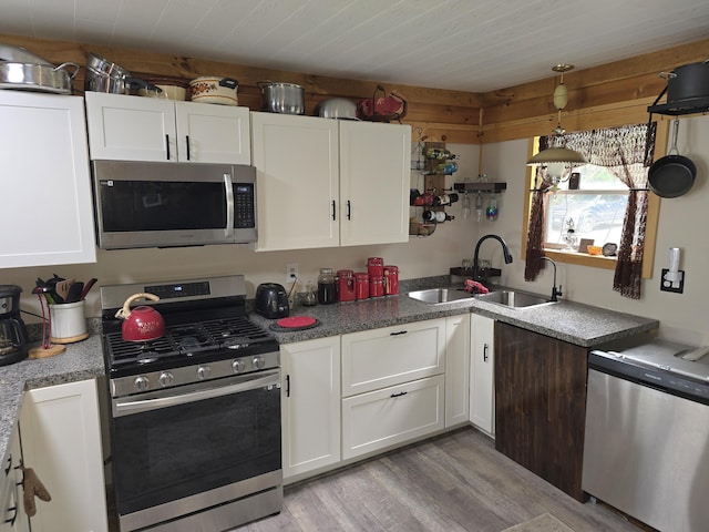 502 Cedar Lake Rd, Millinocket, ME 04462 - kitchen featuring stainless steel appliances, light wood finished floors, white cabinets, and hanging light fixtures