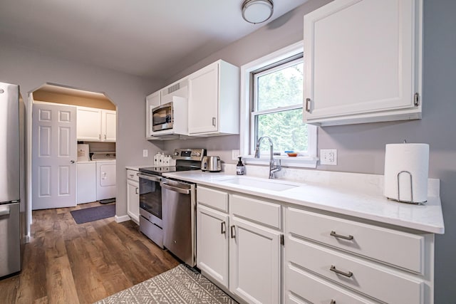 111 Rocky Rd, Woodstock, ME 04219 - kitchen with stainless steel appliances, washer and dryer, white cabinetry, and dark wood-style floors