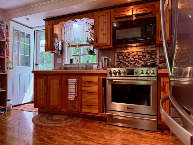 49 31st St, Shapleigh, ME 04076 - kitchen with appliances with stainless steel finishes, crown molding, brown cabinets, tasteful backsplash, and light wood-style floors